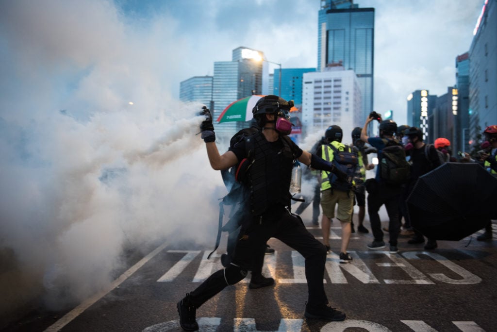 A protester in Hong Kong throws back a tear-gas round at police during an unauthorized demonstration on the fifth anniversary of the denial of universal suffrage to Hong Kongers by the Chinese state. (Photo by Aidan Marzo/SOPA Images/LightRocket via Getty Images)