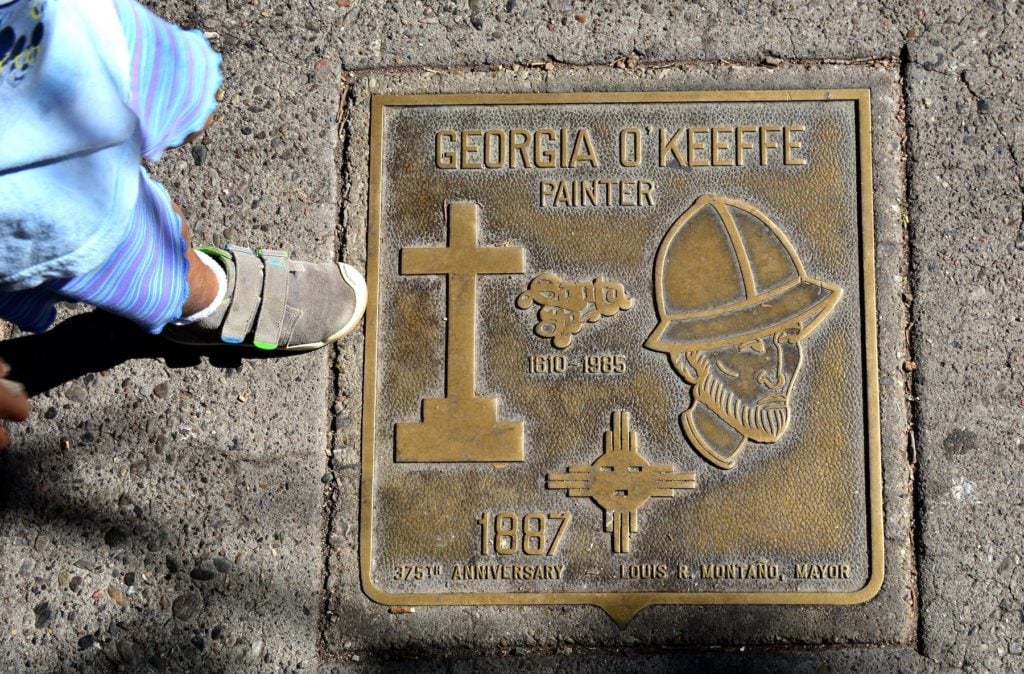 A bronze plaque honoring painter Georgia O'Keeffe is embedded in a sidewalk in front of the New Mexico Museum of Art in Santa Fe, New Mexico. Photo by Robert Alexander/Getty Images.