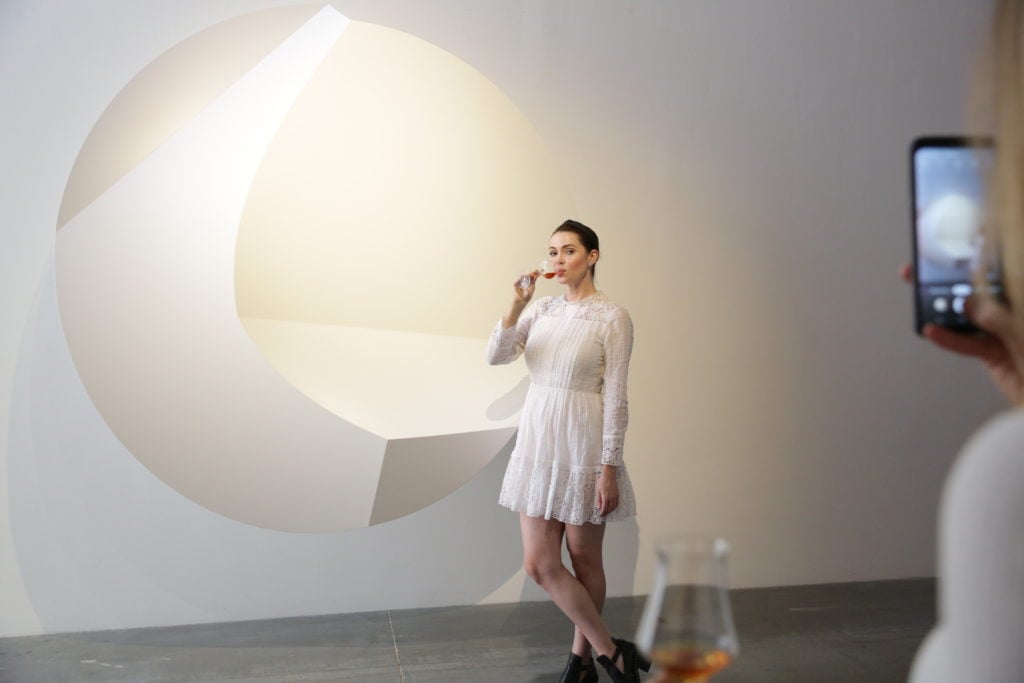 A guest sipping the rare cognac before one of Smith's artworks. Photo courtesy artnet.