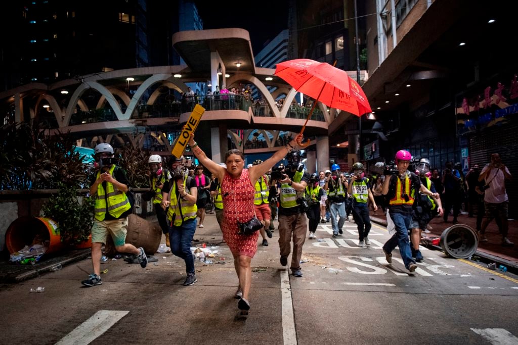 A woman holds up an umbrella and a license plate that reads "love" during a protest in Hong Kong. Photo by Nicolas Asfouri/AFP/Getty Images.
