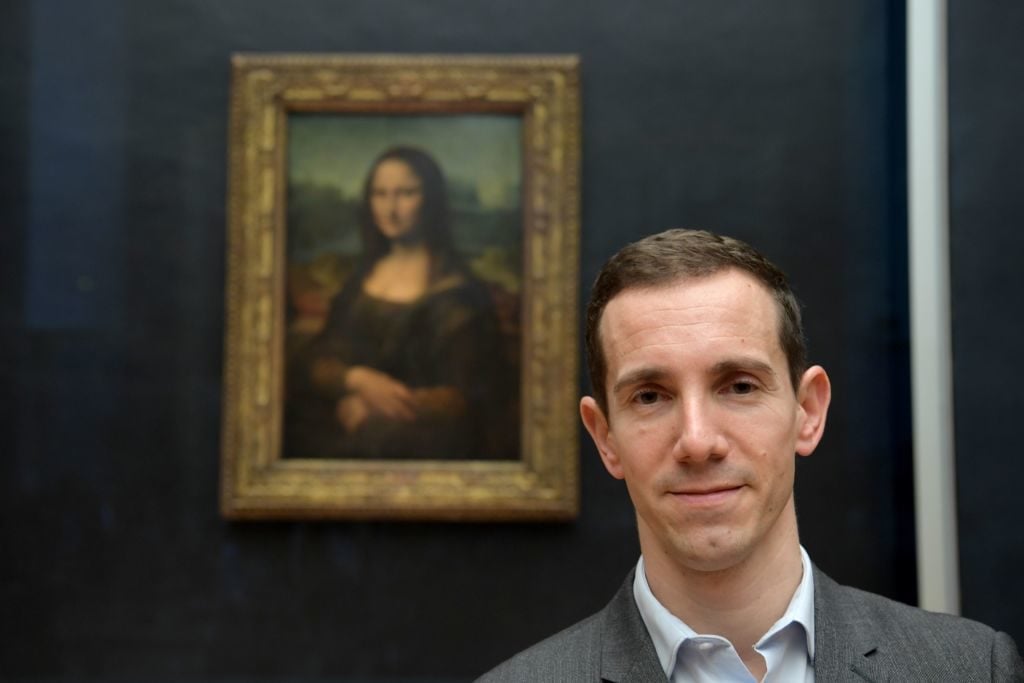 Vincent Delieuvin poses next to Mona Lisa after it was returned at its place at the Louvre Museum in Paris. Photo by Eric Feferberg/AFP via Getty Images.