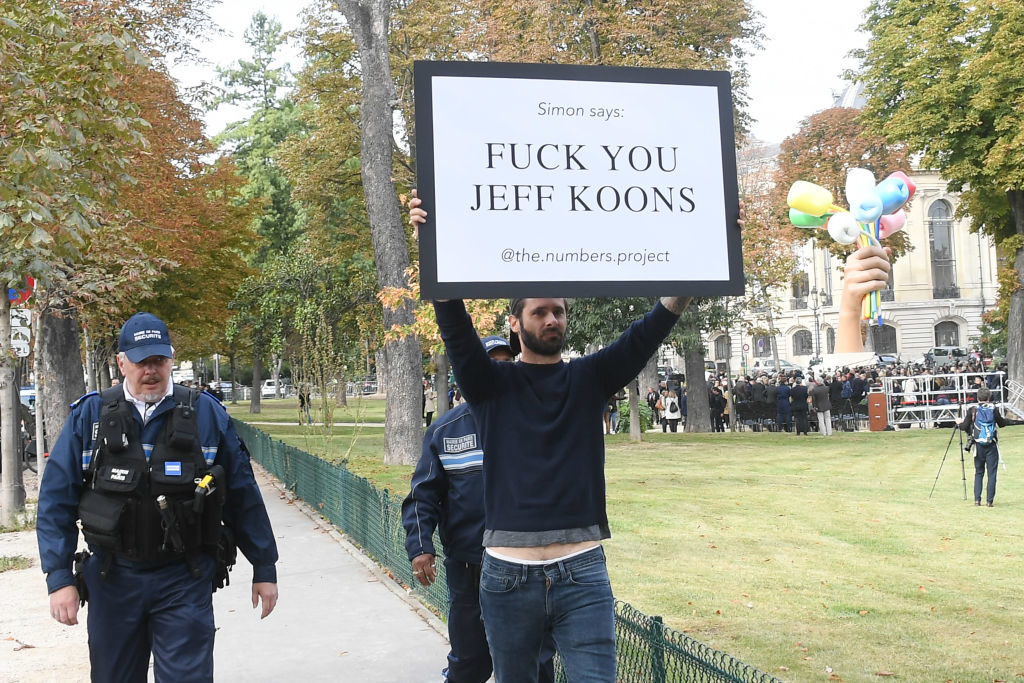 A Koons detractor protests at the inauguration of Jeff Koons's Bouquet of Tulips in Paris. Photo by Stephane Cardinale - Corbis/Corbis via Getty Images.