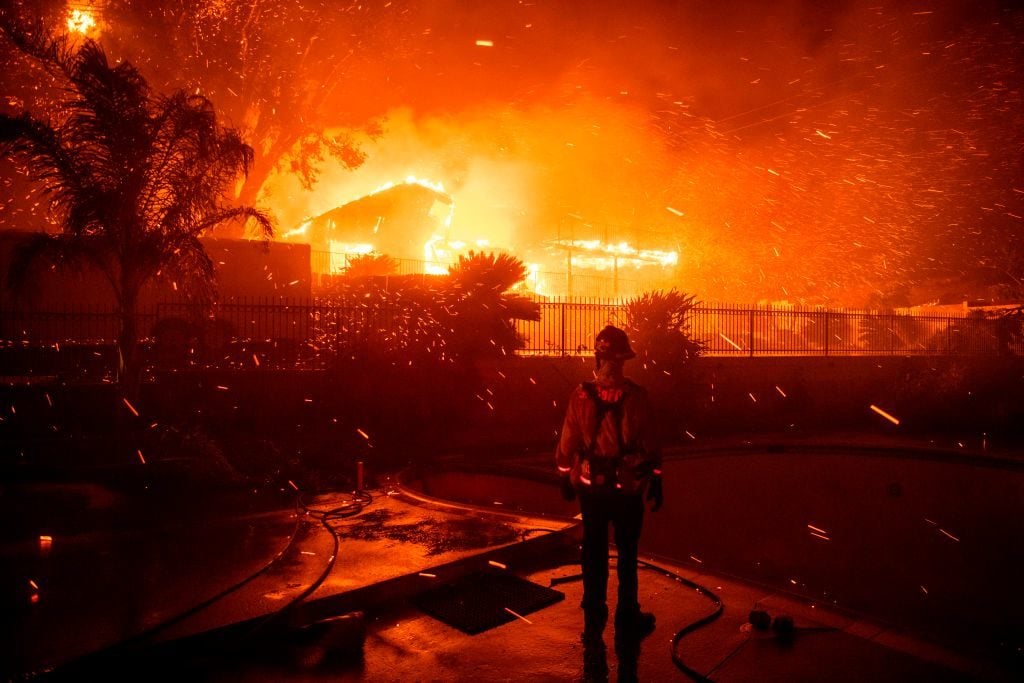 A firefighter looks on as homes burn and wind blows embers during the Hillside Fire in the North Park neighborhood of San Bernardino, California on October 31, 2019. (Photo by Josh Edelson / AFP) (Photo by JOSH EDELSON/AFP via Getty Images)