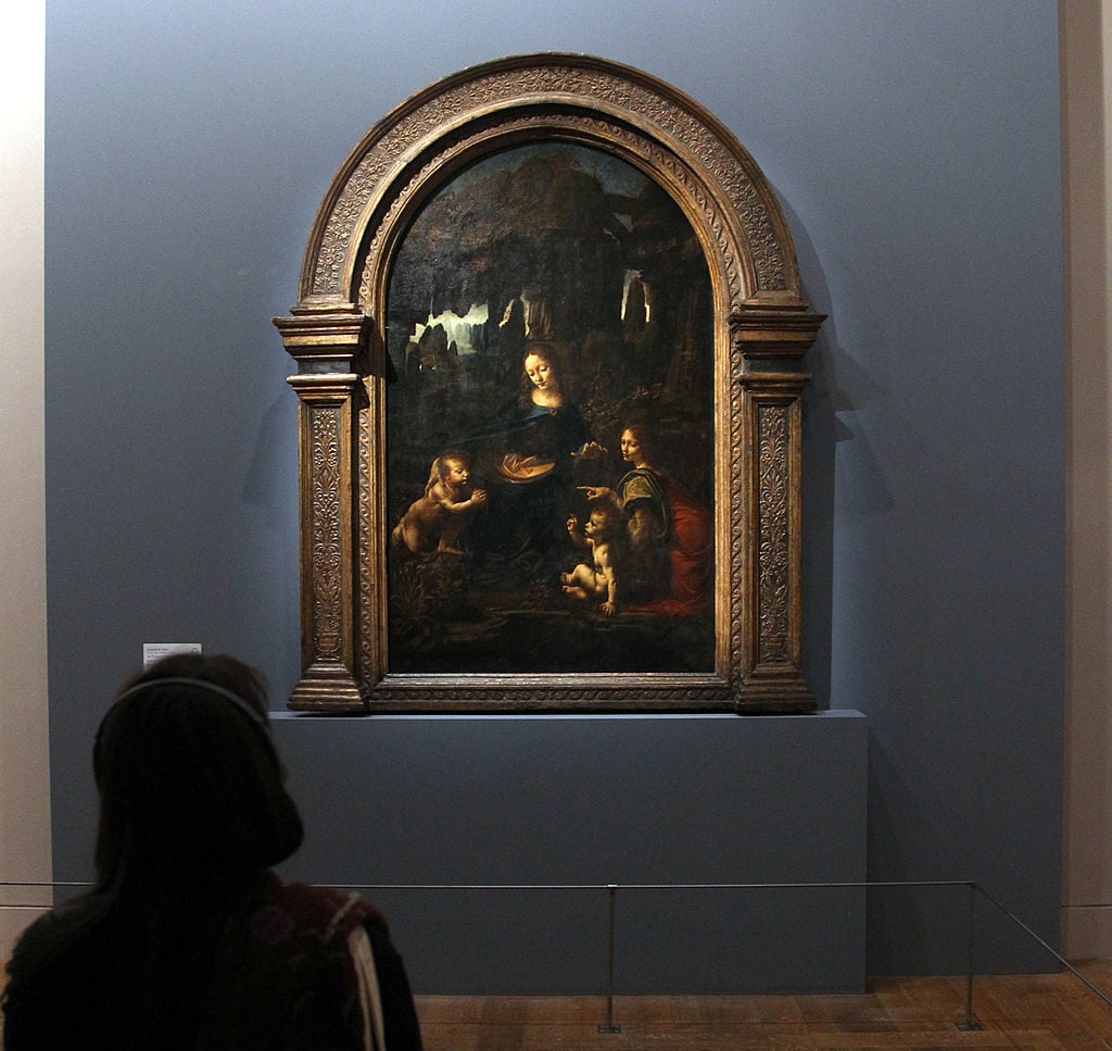 A visitor looks at the painting <i>The Virgin of the Rocks</i> at the Louvre. Photo by Jacques Demarthon/AFP/Getty Images.