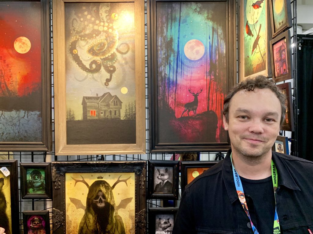 An artist with his work in Artist Alley at New York Comic Con. Photo by Sarah Cascone. 