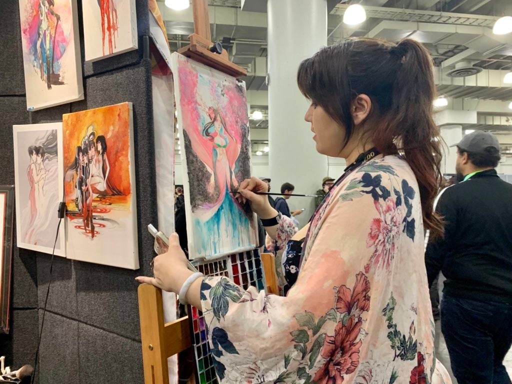 Nen Chang paints at her Artist Alley booth at New York Comic Con. Photo by Sarah Cascone.