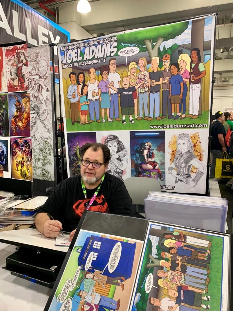 <em>King of the Hill</em> character designer Joel Adams at his Artist Alley booth at New York Comic Con. Photo by Sarah Cascone. 