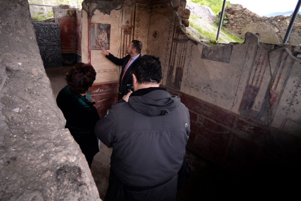 A curator at the Pompeii Archaeological Park discusses the Leda and the Swan fresco uncovered in November 2018 in the Regio V dig site at Pompeii. Photo by Filippo Monteforte / AFP via Getty Images.
