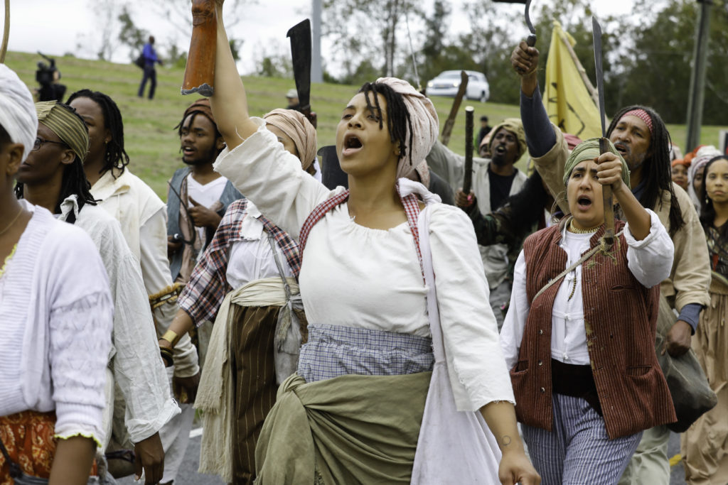 Dread Scott leading the "army of the enslaved" making its way across the 26-mile path through Louisiana. Costumes designed by Alison Parker, Photo: Soul Brother. Courtesy of SRR.