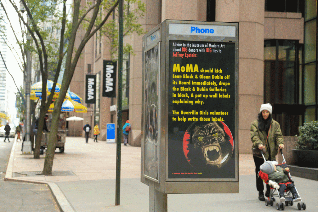 Art in Ad Places has installed a Guerrilla Girls poster calling on the Museum of Modern Art to cut ties with donors linked to Jeffrey Epstein in a phone booth near the New York museum. Photo by Luna Park, courtesy of Art in Ad Places.