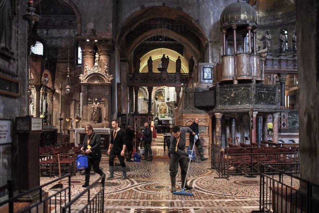 People mop the floor of the flooded St. Mark's Basilica after the floods of November 13 in Venice. Photo by Marco Bertorello/AFP via Getty Images.