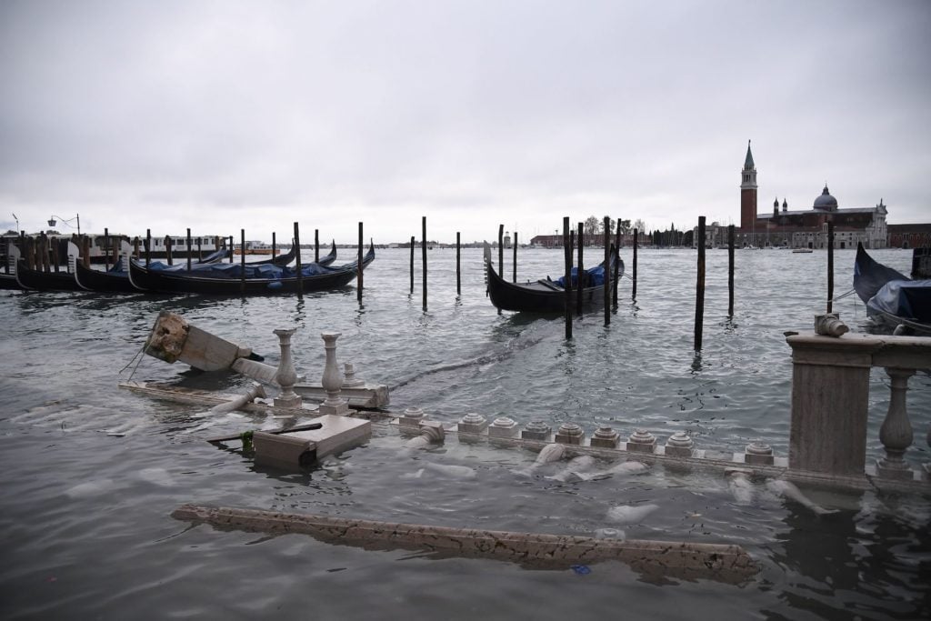 Moored gondolas and a damaged baluster are pictured at the Riva degli Schiavoni embankment, with the basilica of San Giorgio Maggiore in the background on November 12 in Venice. Photo by Marco Bertorello/AFP via Getty Images.