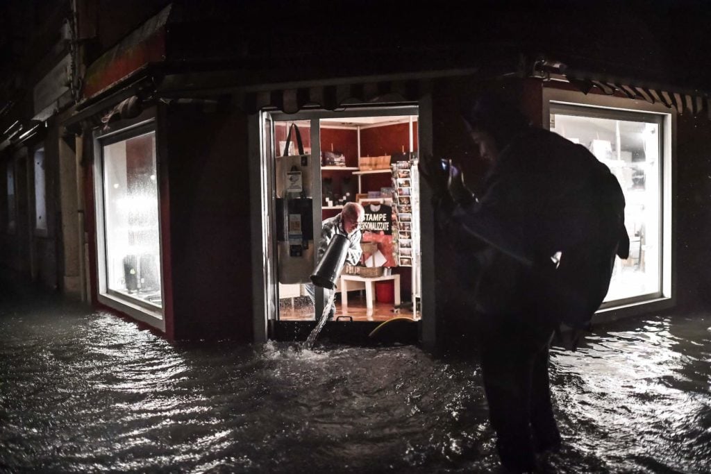 A shop owner clears his flooded premises on November 12, 2019 in Venice. Photo by Marco Bertorello/AFP via Getty Images.