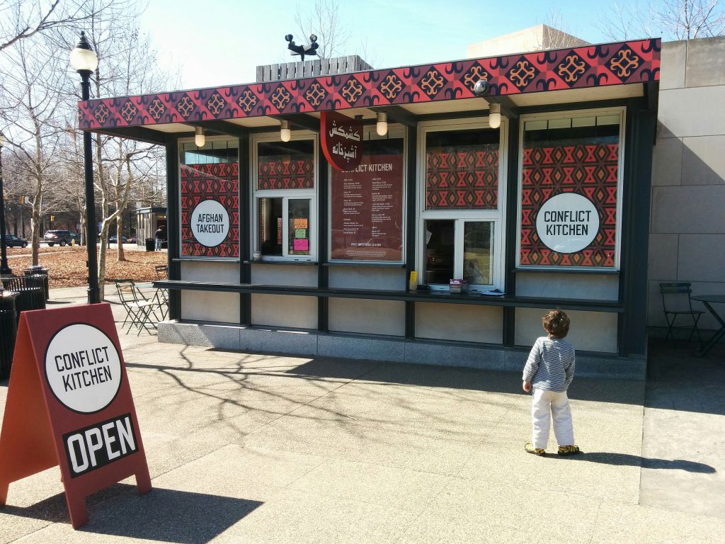 Conflict Kitchen's Schenley Plaza location, decorated for an Afghan menu in 2014. Photo by Ragesoss, Creative Commons <a href=https://creativecommons.org/licenses/by-sa/3.0/deed.en target="_blank" rel="noopener"> Attribution-Share Alike 3.0 Unported</a> license.