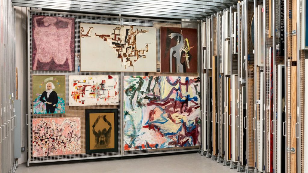 Pull-out racks of art storage, with one rack pulled out to show works by Jean Dubuffet, Martin Barré, Wifredo Lam, Willem de Kooning, David Hammons, Paul Wonner, Cecilia Vicuña, and Maria Helena Vieira da Silva. Photo by David M. Heald, courtesy of the Solomon R. Guggenheim Museum.
