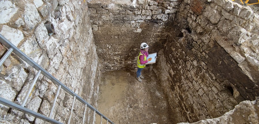 An archaeologist standing in the 15th-century cesspit under the Courtauld Institute. © MOLA.