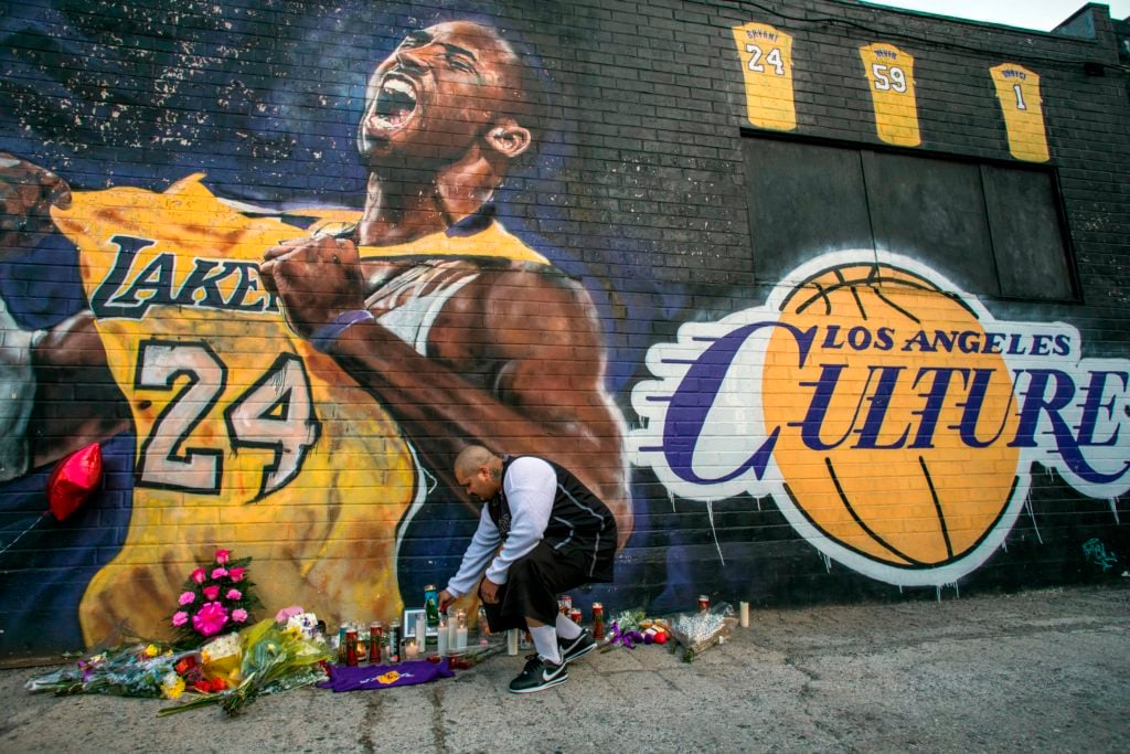 Luis Villanueva lights a candle in front of a Kobe Bryant mural by Jonas Never in downtown Los Angeles on January 26, 2020. Nine people were killed in the helicopter crash which claimed the life of NBA star Kobe Bryant and his 13-year-old daughter, Gianna Bryant. Photo by Apu Gomes/AFP/Getty Images.