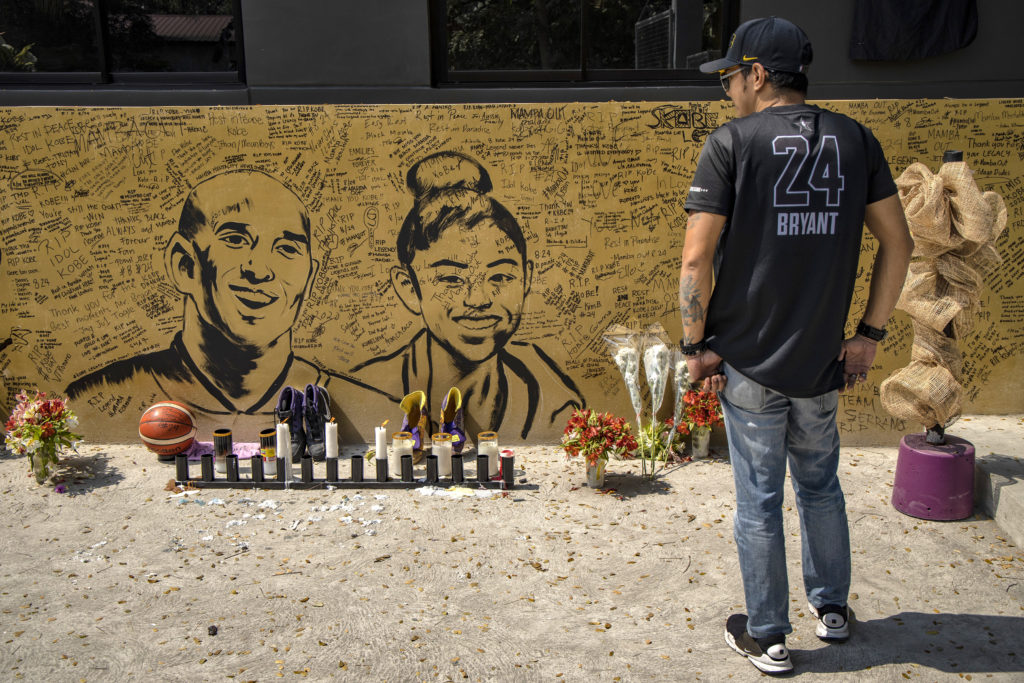 A basketball fan looks on at a mural of former NBA star Kobe Bryant and his daughter, Gianna Bryant, outside the "House of Kobe" basketball court on January 28, 2020 in Valenzuela, Metro Manila, Philippines. Photo by Ezra Acayan/Getty Images.