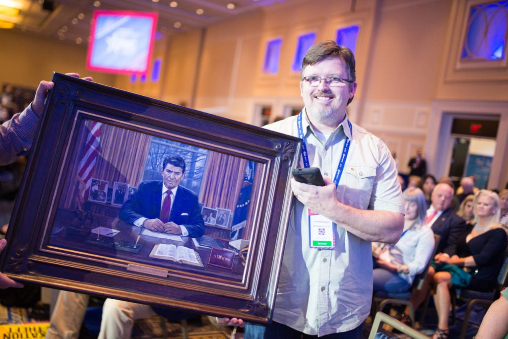 Painter Jon McNaughton shows off a portrait of President Reagan at a taping of Sean Hannity's Fox News TV show. Photo by Zach D Roberts/NurPhoto via Getty Images.