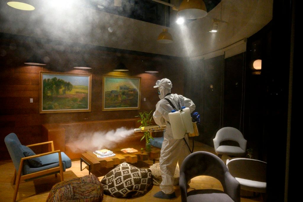 A worker wearing a protective suit uses a fogging machine to disinfect a business establishment in Shanghai on February 9, 2020. Photo by Noel Celis/AFP via Getty Images.
