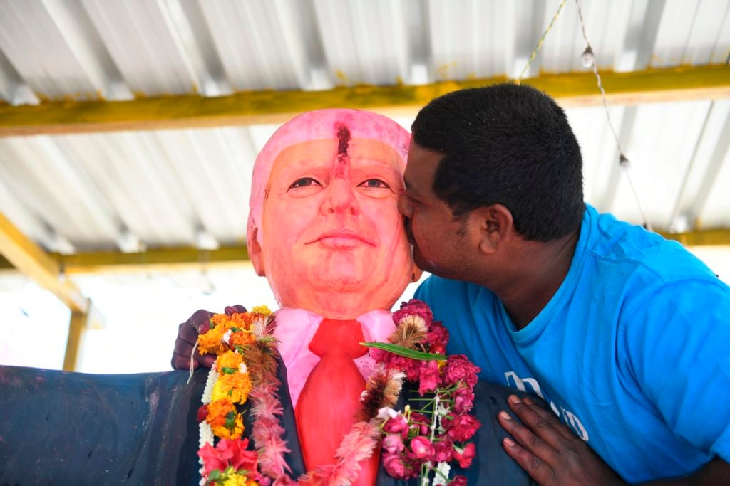 Bussa Krishna, 33, kisses a statue of US President Donald Trump after offering prayers at his homemade shrine to the world leader. Photo by Noah Seelam/AFP/Getty Images.
