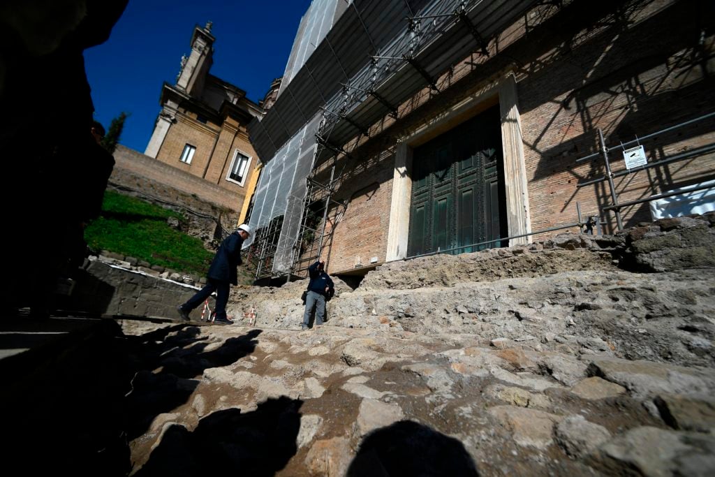 People stand by the access to an ancient tomb thought to belong to Rome's founder Romulus on February 21, 2020 at the Curia - Comitium in the Roman Forum of Rome. Photo by Filippo Montforte/AFP via Getty Images.