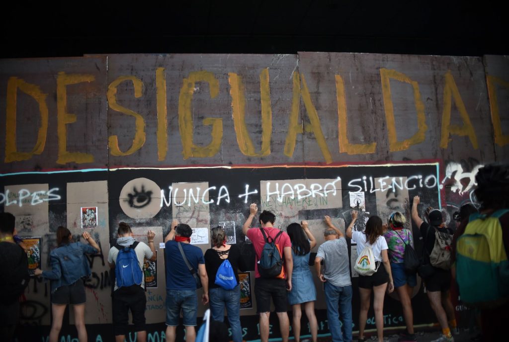 People demonstrate under a graffiti reading "Inequality" during a protest demanding greater social reform from Chilean President Sebastian Pinera in Santiago on November 12, 2019. Photo by Rodrigo Arangua/AFP via Getty Images.