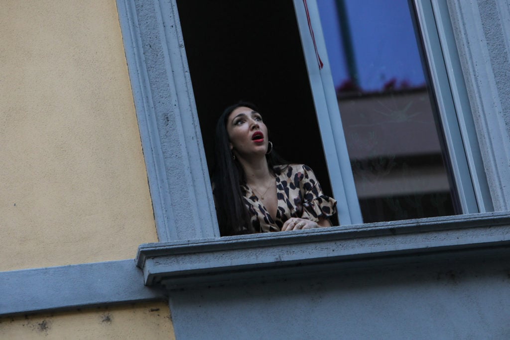 Laura Baldassari sings from the window on March 13, 2020, during a flash mob where people stood sang or played music on balconies, to make people feel united in the quarantine. Photo by Mairo Cinquetti/NurPhoto via Getty Images.