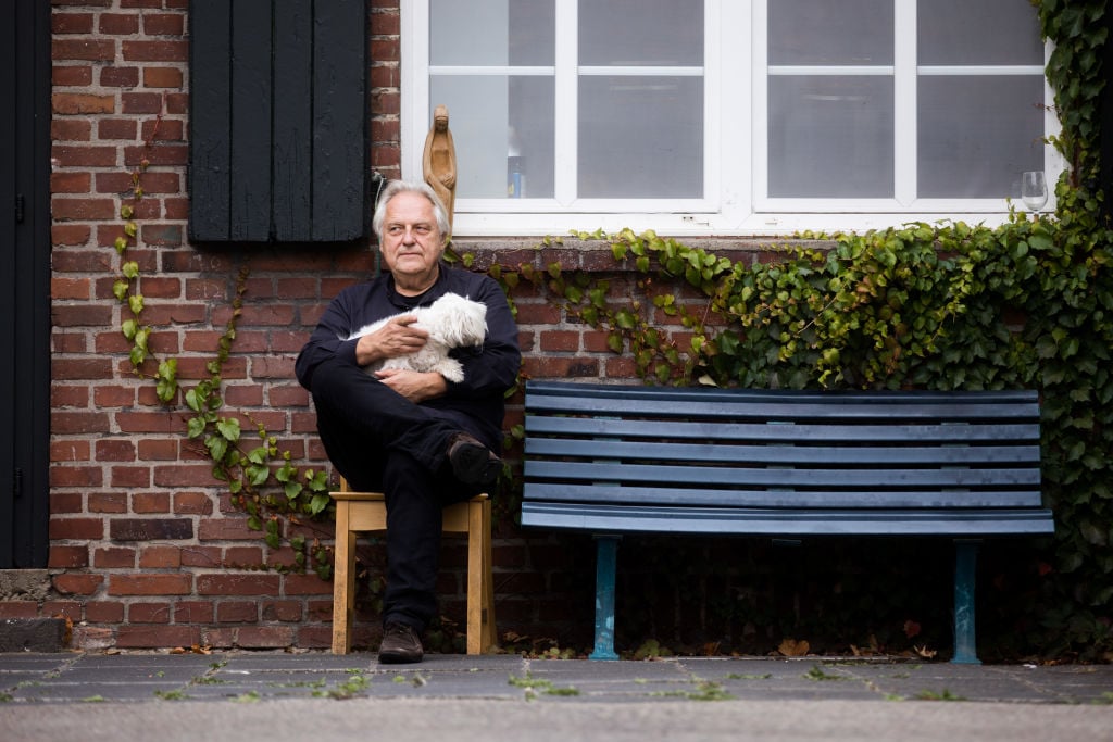 Helge Achenbach sits in front of the Kunsthof. Achenbach is committed to politically persecuted artists on the former farm on the Lower Rhine. Photo by Rolf Vennenbernd/picture alliance via Getty Images.