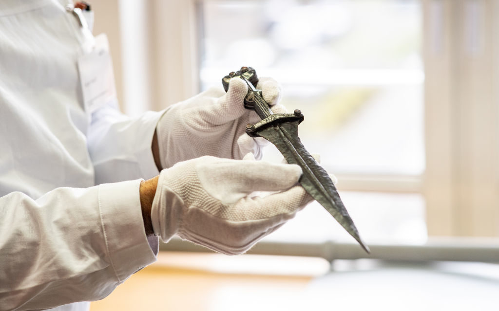 A restorer of the LWL-Archaeology for Westphalia holds a 2000 year old dagger of a legionary in his hands in North Rhine-Westphalia, Münster on February 14, 2020. Photo: Guido Kirchner/dpa via Getty Images.