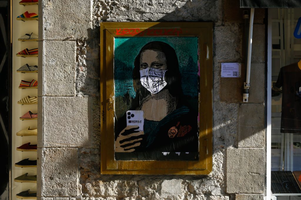 A coronavirus street art poster by Italian urban artist Salvatore Benintende aka "TVBOY" depecting Leonardo da Vinci's Mona Lisa wearing a protective facemask in Barcelona. Photo by Pau Barrena/AFP via Getty Images.