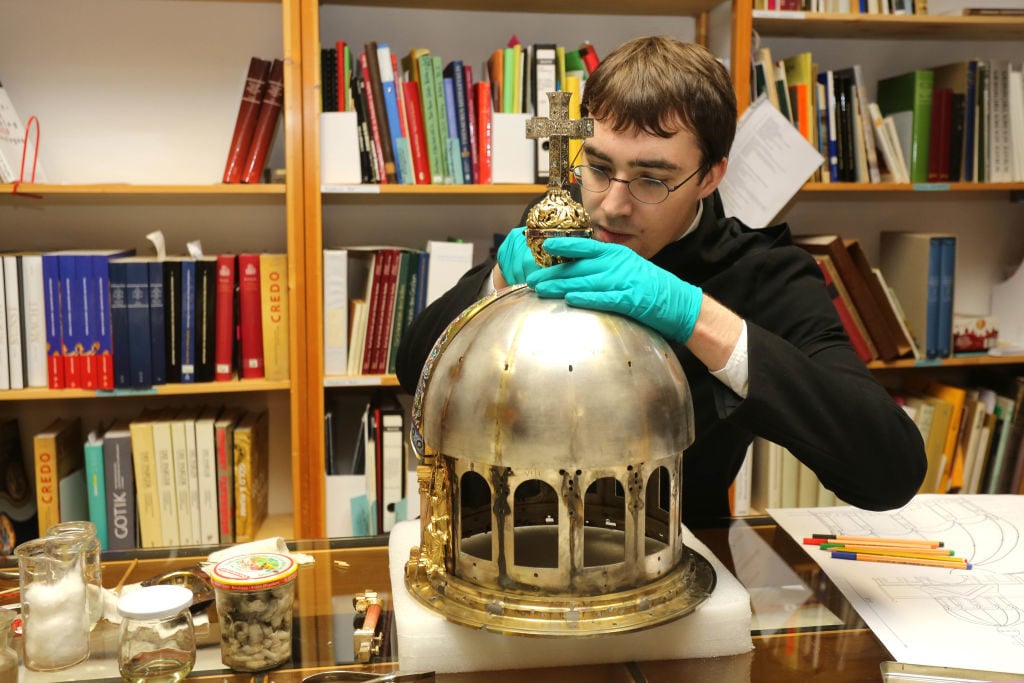 Luke Jonathan Koeppe, a student of restoration and conservation science, cleans and preserves the shrine of St. Corona. Photo by Ralf Roeger/picture alliance via Getty Images.