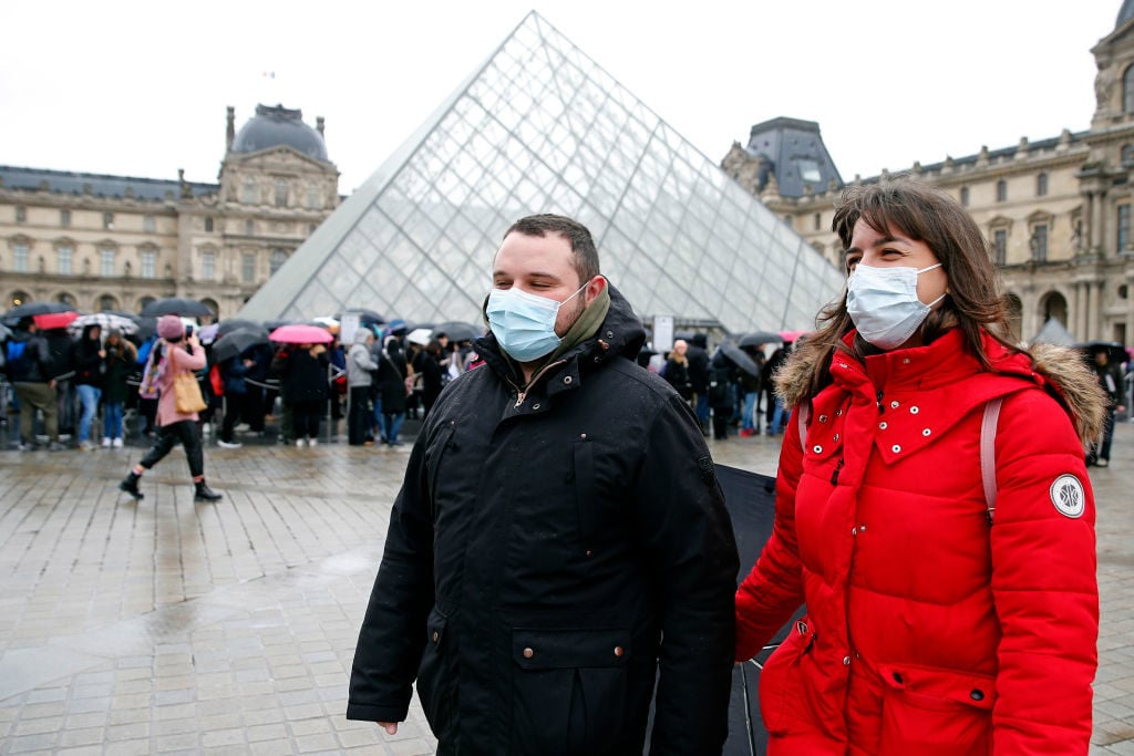 Tourists wearing face masks walk past the Louvre Museum as the museum was closed for a staff meeting about the coronavirus outbreak on March 2. Photo by Chesnot/Getty Images.