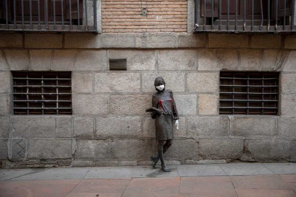 A protective mask and gloves are placed on a statue in Madrid Center. (Photo by Pablo Blazquez Dominguez/Getty Images)