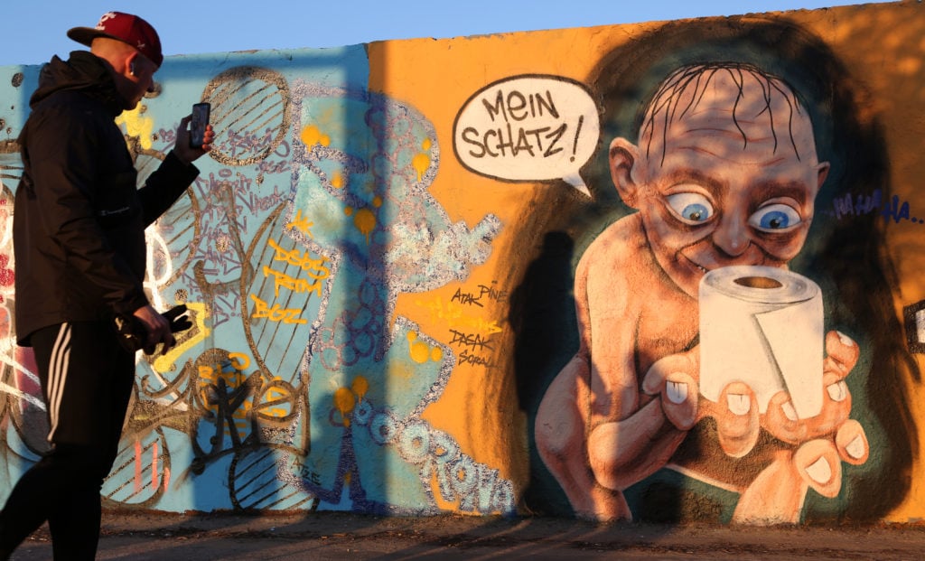 Street art in Berlin featuring the Lord of the Rings character Gollum holding a roll of toilet paper, a shopping item hoarded by consumers during the coronavirus pandemic crisis. Photo by Adam Berry/Getty Images.