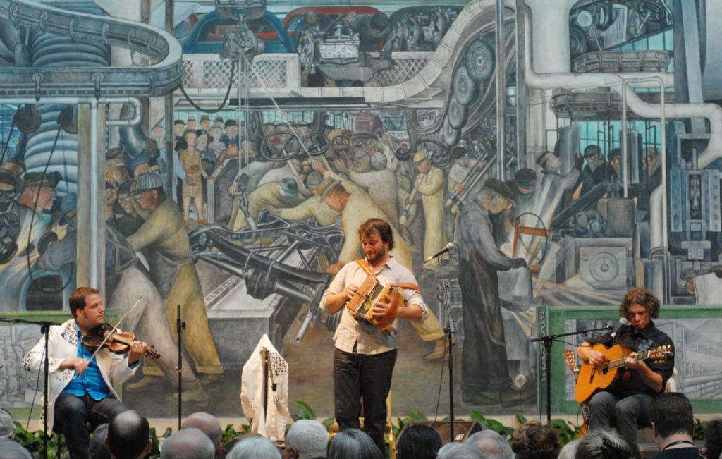 Performers in front of the Detroit Industry murals by Mexican artist Diego Rivera at the Detroit Institute of Arts in 2012. (Photo by Paul Warner/Getty Images)