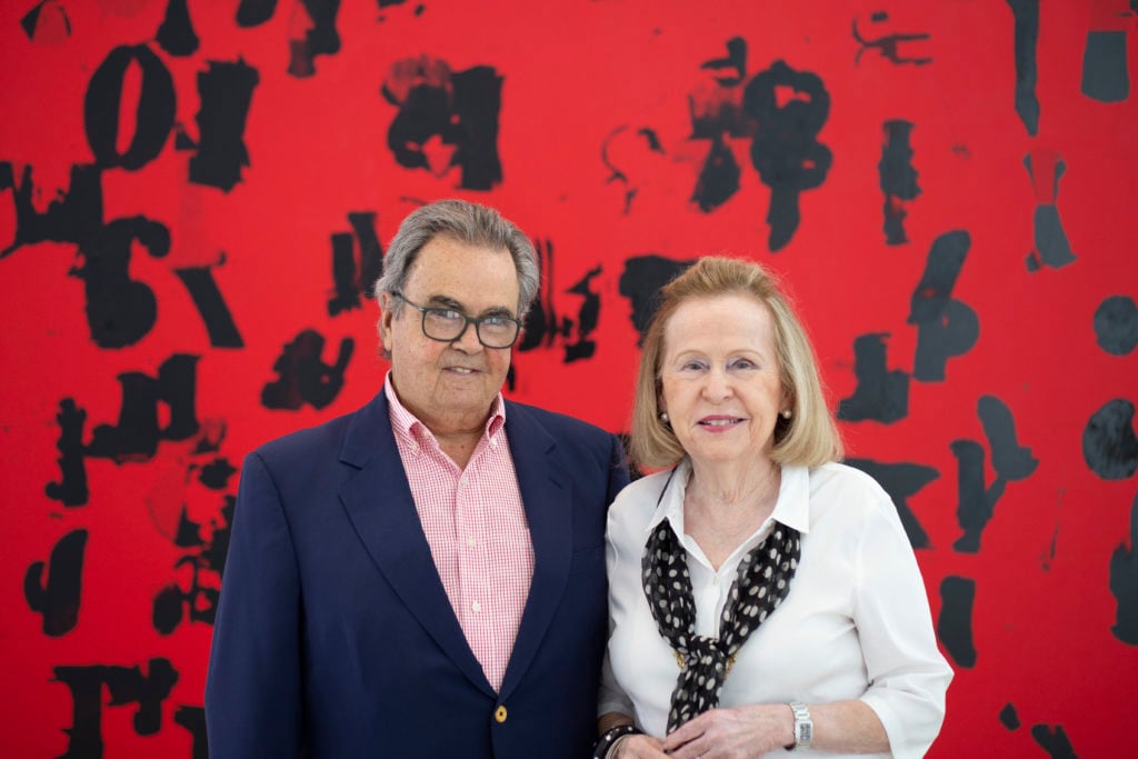 Portrait of Rosa and Carlos de la Cruz with one of their recent acquisitions, Glenn Ligon Debris Field (Red) # 3 (2018). Courtesy of the de la Cruz Collection.