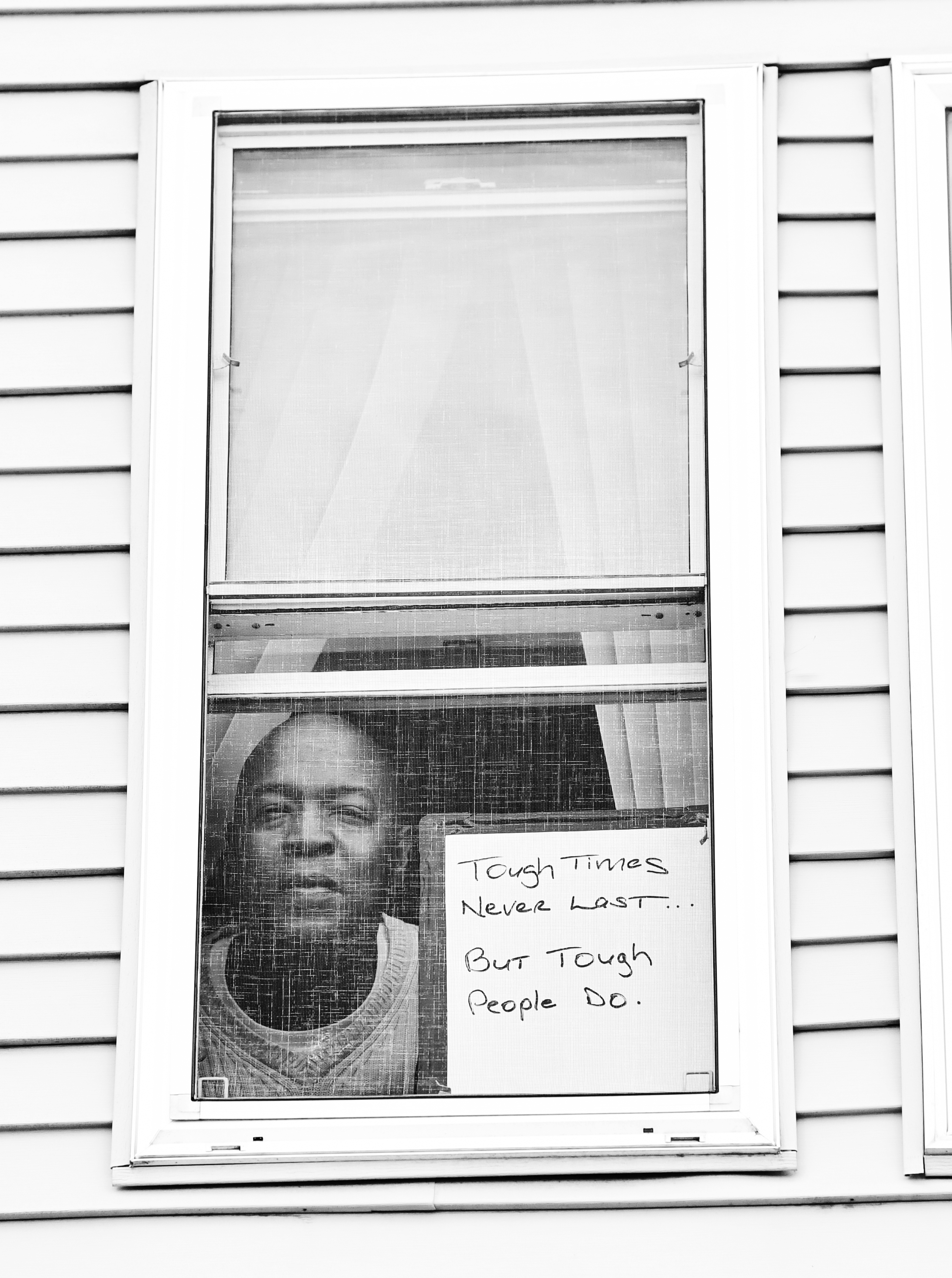 Robert E. Clark Jr. poses for "Words at the Window: Self Isolation and The Coronavirus," a portrait series by Shutterstock staff photographer, Stephen Lovekin, shot around the Ditmas Park neighborhood of Brooklyn, New York. Photo courtesy of Shutterstock.