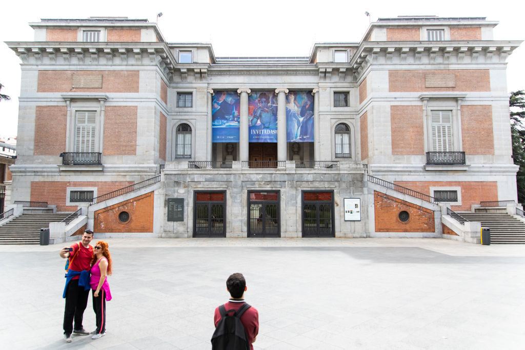 A man looks at the closed Prado Museum while a couple takes a selfie on in Madrid, Spain. Photo: Patricia J. Garcinuno/Getty Images.