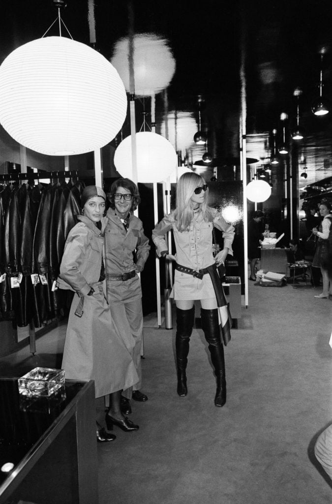 Yves Saint Laurent, designer pictured inside his first London Rive Gauche store on New Bond Street, London, opening day of boutique, and with muses Louise de La Falaise, aka Loulou (left) and Betty Catroux (right), 10th September 1969. (Photo by Dorean Spooner/Mirrorpix/Getty Images).