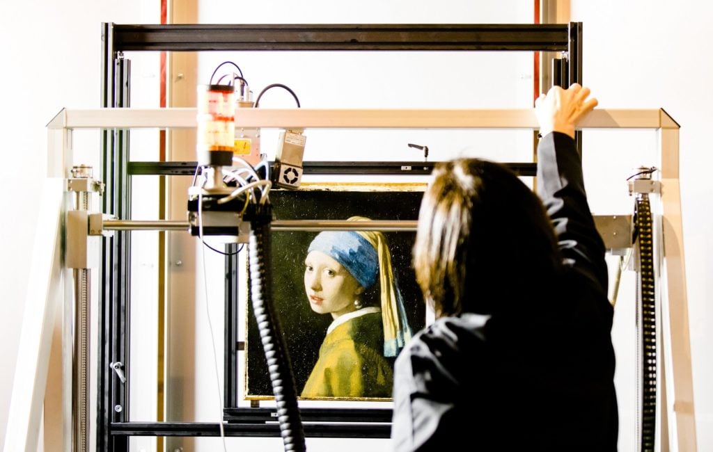 A researcher at the Mauritshuis gallery in The Hague places Johannes Vermeer’s Girl with a Pearl Earring inside a scanner. Photo by Bart Maat/ANP/AFP via Getty Images. 
