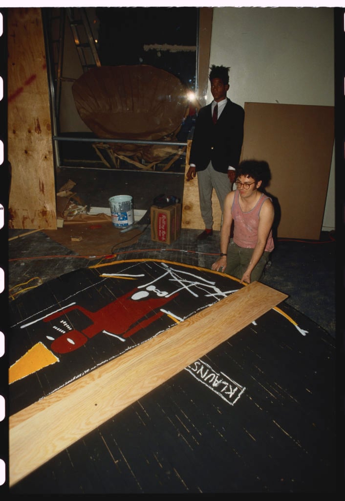 Jean-Michel Basquiat looks on as one of his artworks is inspected at Area, a Manhattan nightclub, in January 1980. Photo by Nick Elgar/Corbis/VCG via Getty Images.