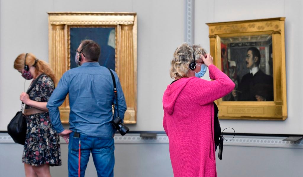 Visitors wearing face masks look at paintings at the Alte Nationalgalerie (Old National Gallery) museum in Berlin. Photo by JOHN MACDOUGALL/AFP via Getty Images.