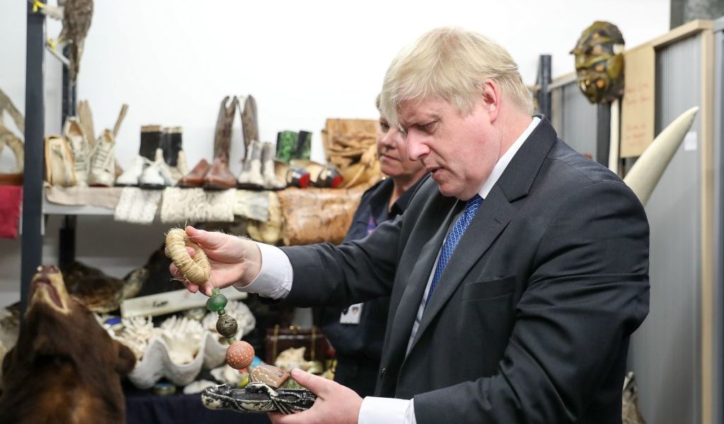 The UK's then-Foreign Secretary Boris Johnson visits the Heathrow "dead shed" to see seized ivory and rhino horn and other items relating to the illegal wildlife trade in 2018. Photo by Andrew Matthews/AFP via Getty Images.