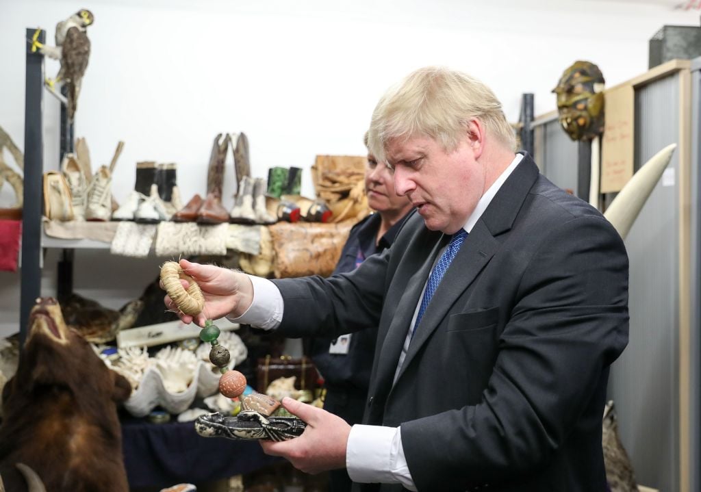 The UK's then-Foreign Secretary Boris Johnson visits the Heathrow "dead shed" to see seized ivory and rhino horn and other items relating to the illegal wildlife trade in 2018. Photo by Andrew Matthews/AFP via Getty Images.