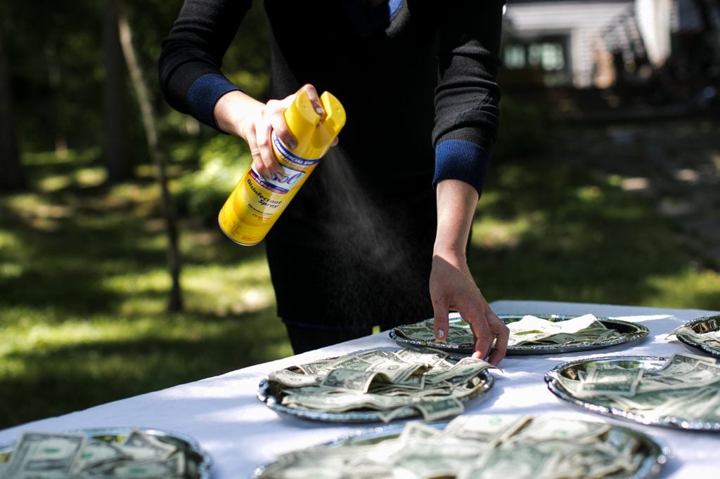 Katherine McMahon sanitizing currency for <em>Free Clean Money</em> a performance art piece with Ray Angry that will be staged later this summer at Guild Hall in East Hampton, New York. Photo by Jessica Dalene. 