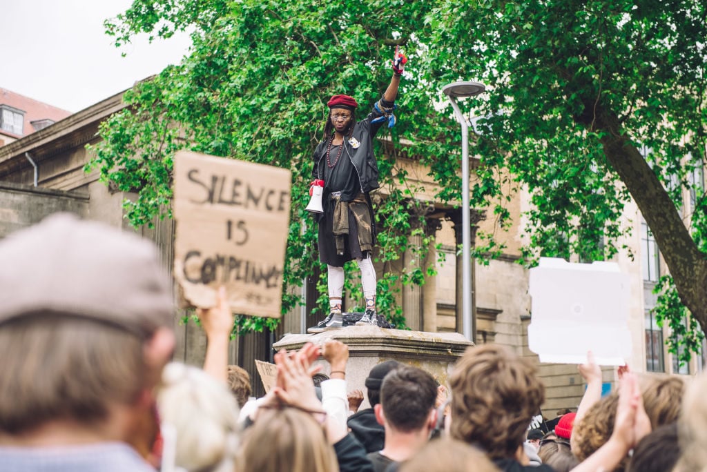 Protester speaks to a crowd from the pedestal that once hosted the statue of Edward Colston. Photo by Giulia Spadafora/NurPhoto via Getty Images.