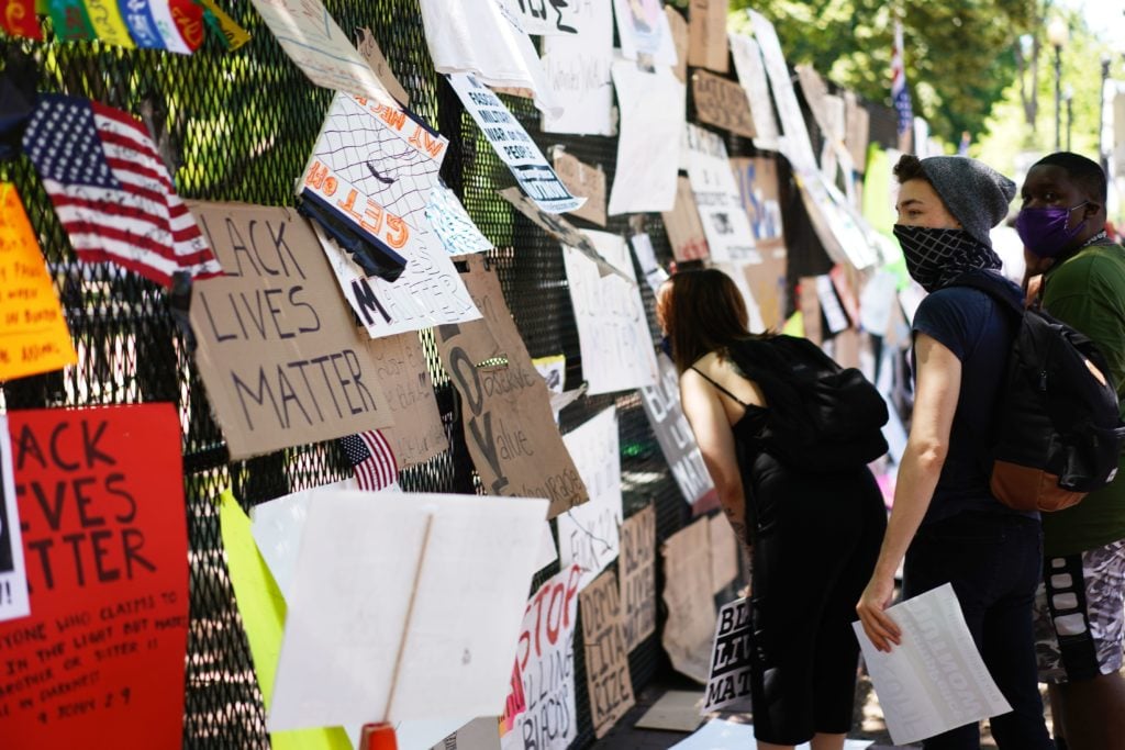 People look at posters and placards on the security fence on the north side of Lafayette Square, near the White House, in Washington, DC on June 8, 2020. Photo by MANDEL NGAN/AFP/Getty Images.