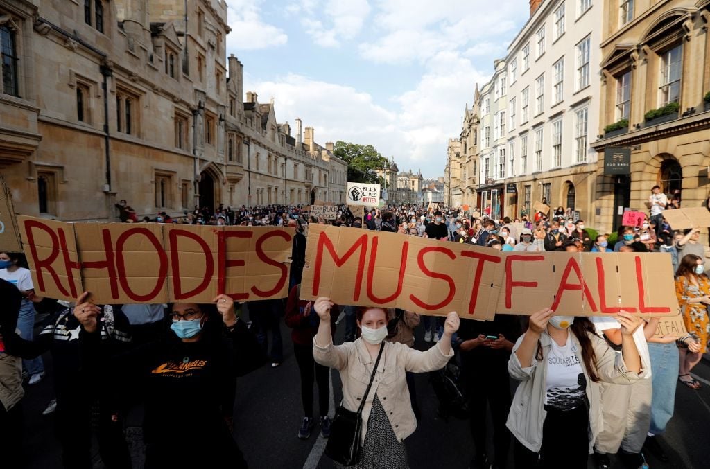 Demonstrators hold placards during a protest arranged by the 'Rhodes Must Fall' campaign, calling for the removal of a statue of British businessman and imperialist Cecil John Rhodes, from outside Oriel College at the University of Oxford. Photo by Adrian Dennis/AFP via Getty Images.