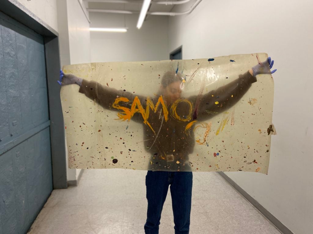 The SAMO-tagged tarp, held by an art handler. Photo courtesy Capsule Auctions.